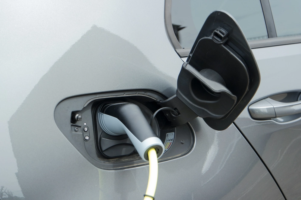 Ladestation für Elektroautos mit eingestecktem Ladestecker in geöffneter Ladebuchse eines silbernen PKW